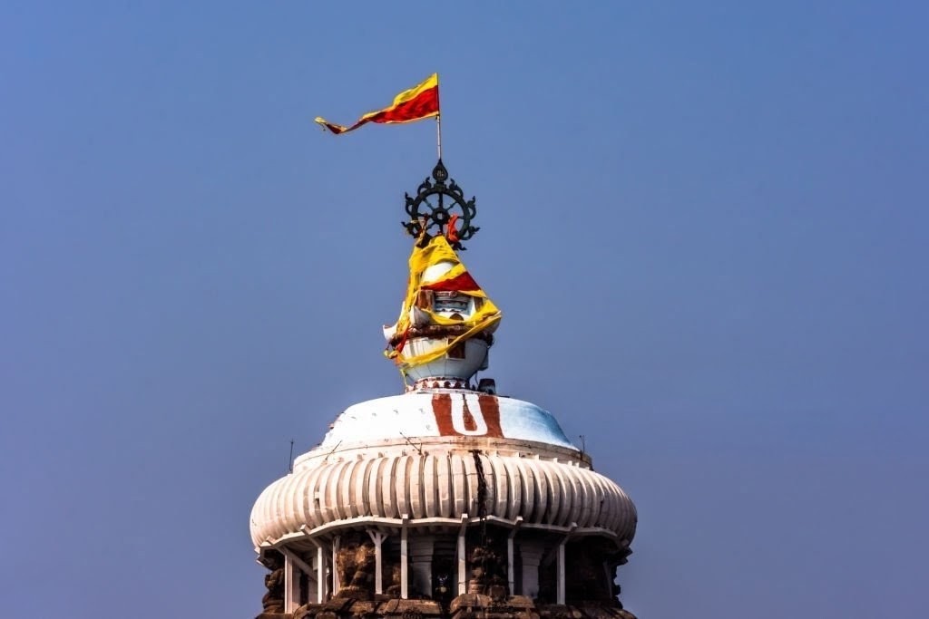Priest changing the flag beneath the Nilachakra atop the temple spire